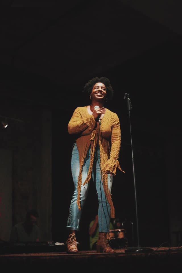Vocalist mid-performance under warm stage lights