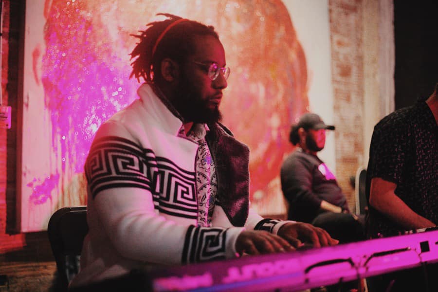 Keyboardist performing under magenta stage lighting